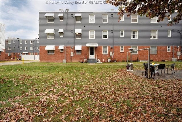 back of property with a yard and central AC