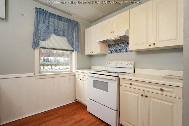 kitchen featuring white cabinetry, electric range, hardwood / wood-style floors, and wood walls