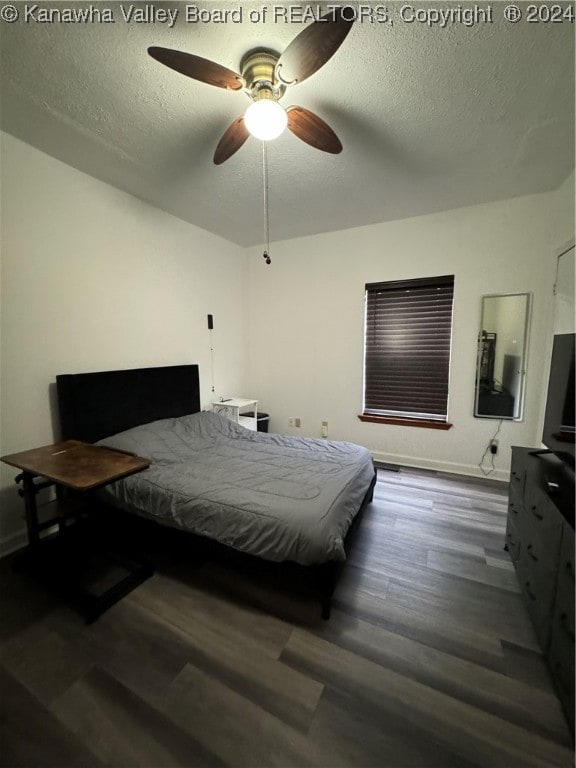 bedroom featuring ceiling fan, dark hardwood / wood-style flooring, and a textured ceiling