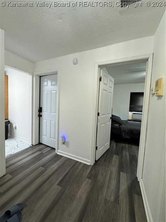 corridor with a textured ceiling and dark hardwood / wood-style floors