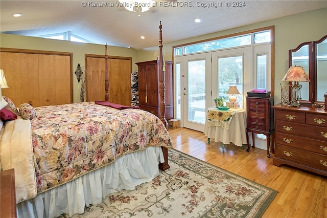 bedroom with a textured ceiling, access to exterior, light hardwood / wood-style floors, and lofted ceiling