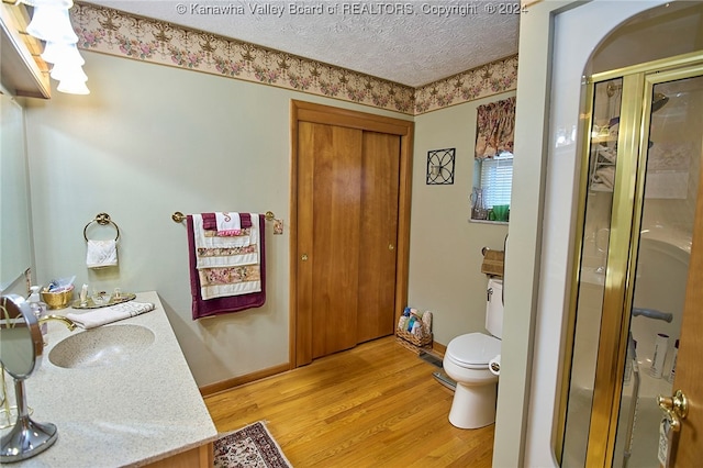 bathroom featuring an enclosed shower, vanity, a textured ceiling, wood-type flooring, and toilet