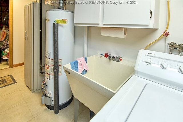 laundry area with cabinets, washer / dryer, light tile patterned floors, and water heater