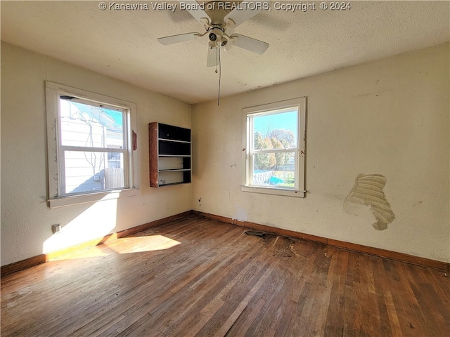 empty room with a textured ceiling, ceiling fan, and dark hardwood / wood-style floors