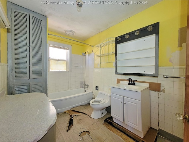 full bathroom featuring vanity, tiled shower / bath combo, toilet, and tile walls