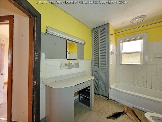 bathroom with a textured ceiling, tile walls, and toilet