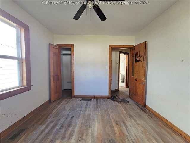 unfurnished bedroom featuring a textured ceiling, multiple windows, dark wood-type flooring, and ceiling fan