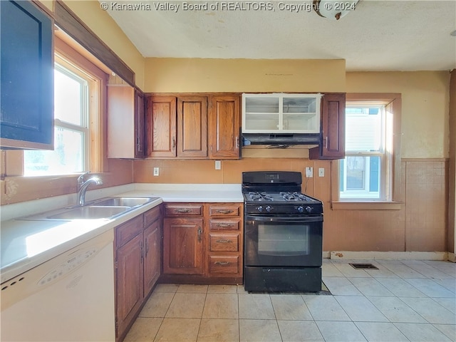 kitchen with white dishwasher, gas stove, light tile patterned flooring, and sink