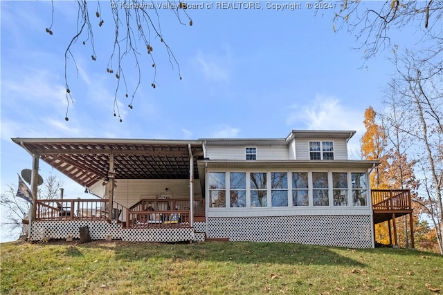 rear view of property featuring a lawn, a wooden deck, and a sunroom