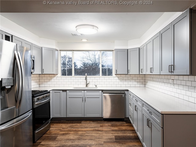 kitchen with appliances with stainless steel finishes, dark hardwood / wood-style floors, gray cabinetry, and sink