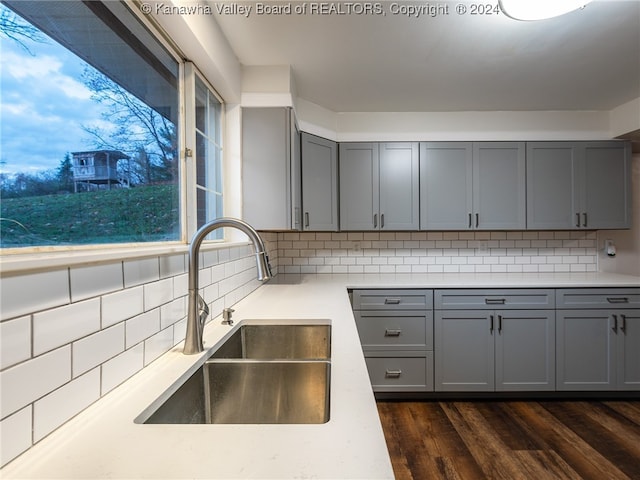 kitchen with gray cabinetry, decorative backsplash, sink, and dark wood-type flooring