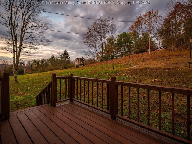 deck at dusk featuring a lawn