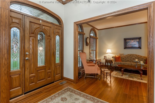 entryway with wood-type flooring and crown molding