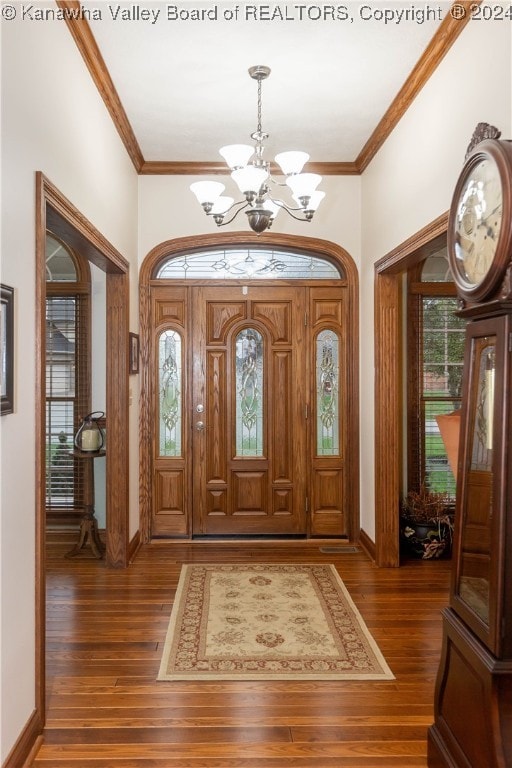 foyer with ornamental molding, dark wood-type flooring, and a notable chandelier