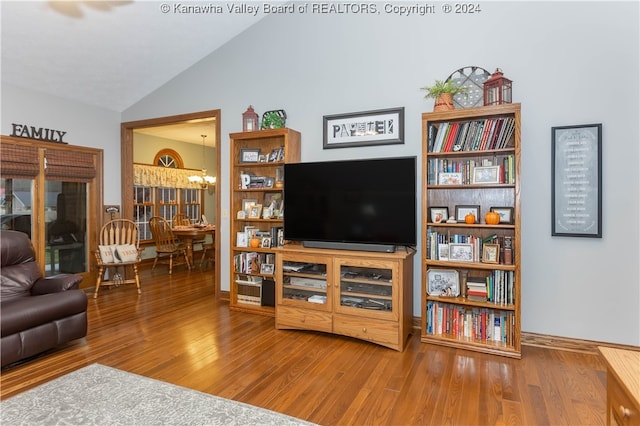 living room featuring vaulted ceiling, wood-type flooring, and an inviting chandelier