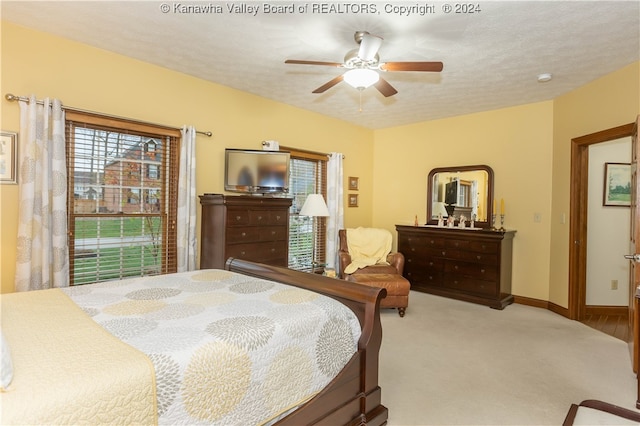 carpeted bedroom featuring ceiling fan and a textured ceiling