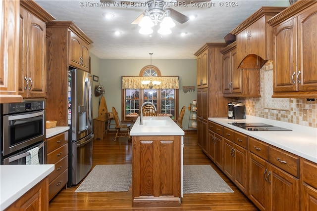 kitchen with wood-type flooring, appliances with stainless steel finishes, a kitchen island with sink, and sink