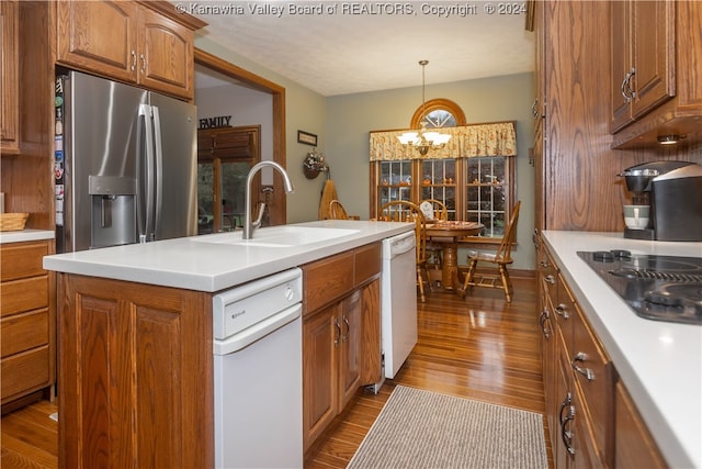 kitchen with sink, stainless steel fridge, hardwood / wood-style floors, an island with sink, and a chandelier