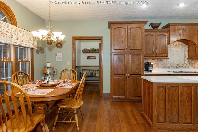 kitchen with hanging light fixtures, dark wood-type flooring, a notable chandelier, a textured ceiling, and black electric stovetop