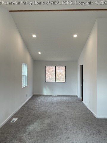 carpeted empty room featuring lofted ceiling