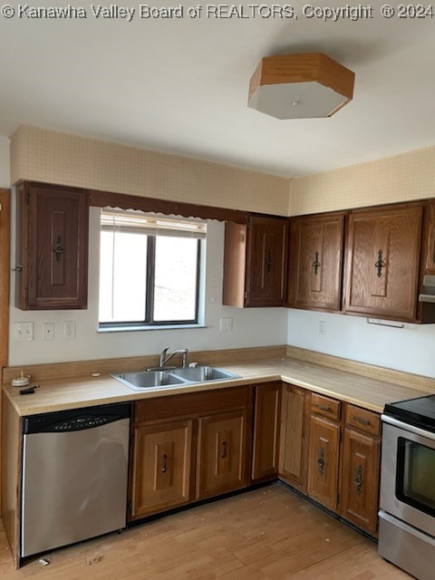 kitchen featuring sink, light wood-type flooring, stainless steel appliances, and extractor fan