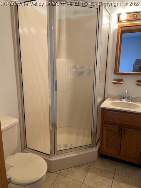 bathroom featuring tile patterned floors, vanity, toilet, and a shower with door