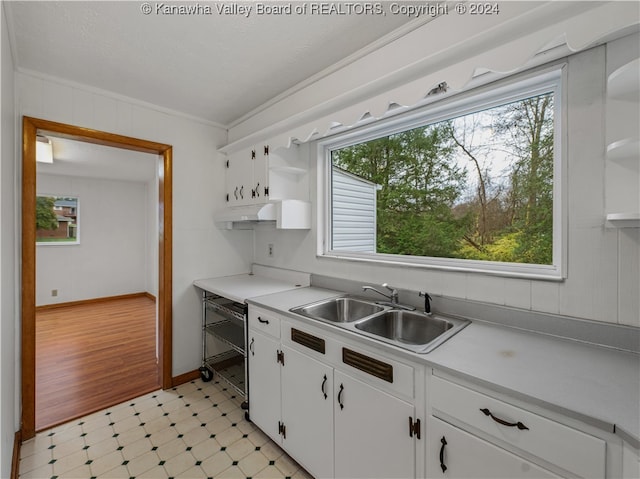 kitchen featuring light hardwood / wood-style floors, white cabinetry, ornamental molding, and sink