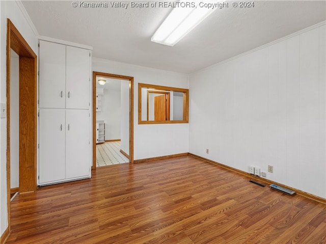 empty room with a textured ceiling, light hardwood / wood-style floors, and ornamental molding