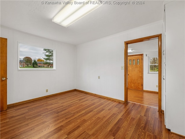 empty room with hardwood / wood-style flooring, plenty of natural light, ornamental molding, and a textured ceiling