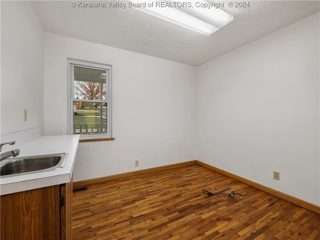 spare room featuring a textured ceiling, hardwood / wood-style flooring, and sink