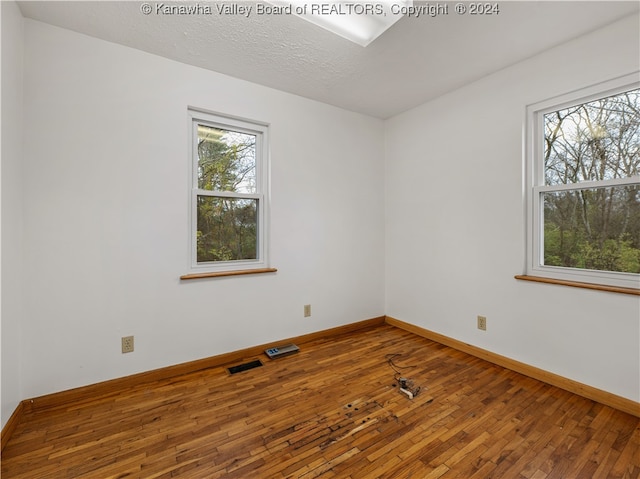 spare room with hardwood / wood-style flooring, a textured ceiling, and a wealth of natural light