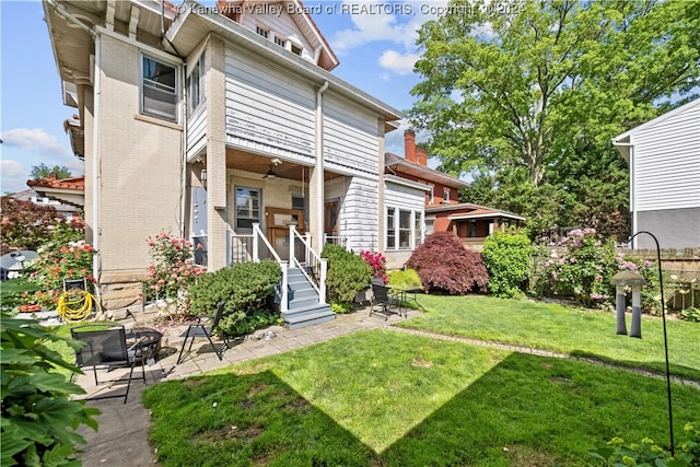 rear view of property featuring a yard and ceiling fan