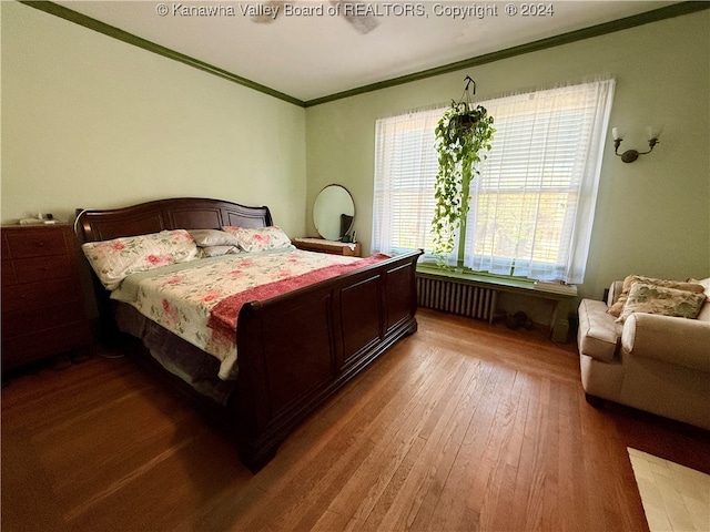 bedroom featuring radiator, wood-type flooring, and ornamental molding