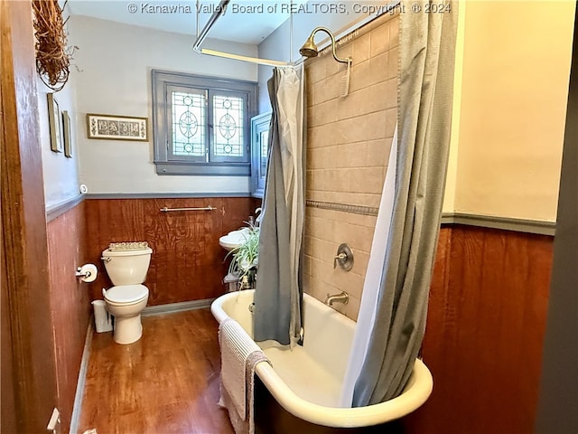 bathroom with shower / bathtub combination with curtain, toilet, wood-type flooring, and wooden walls