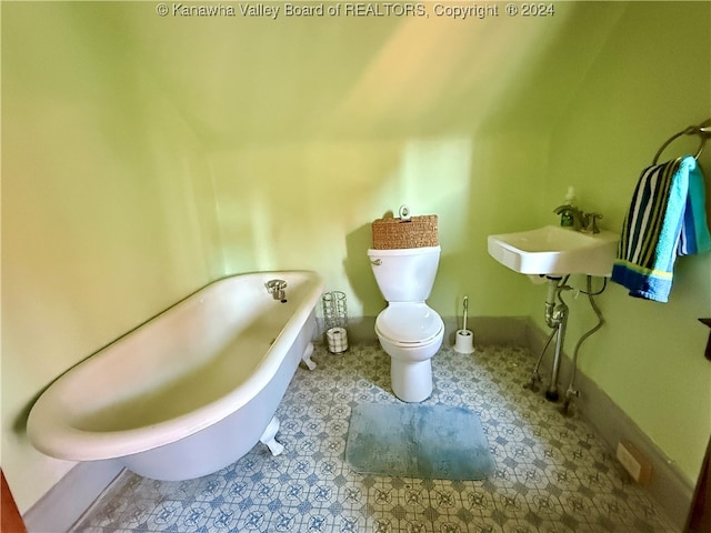 bathroom featuring a tub to relax in, toilet, and sink