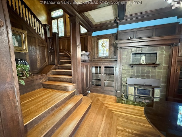 stairs with wooden walls, plenty of natural light, and coffered ceiling