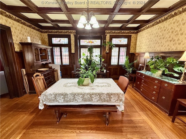 dining area with a chandelier, beam ceiling, light wood-type flooring, and coffered ceiling