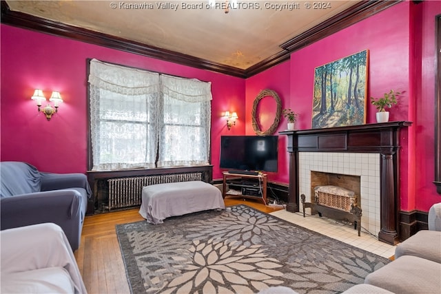 living room with a tile fireplace, radiator heating unit, wood-type flooring, and ornamental molding