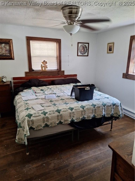 bedroom with a textured ceiling, ceiling fan, dark wood-type flooring, and a baseboard radiator