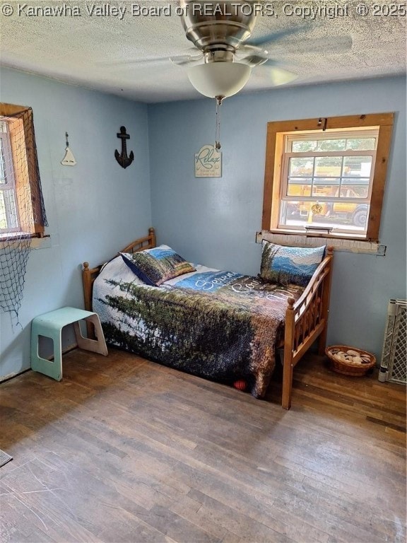 bedroom featuring ceiling fan, hardwood / wood-style floors, and a textured ceiling