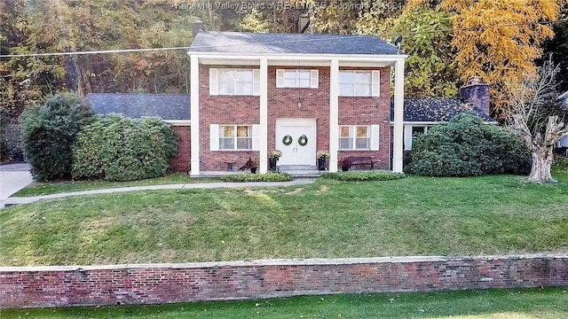 view of front of house featuring a front lawn, brick siding, and a chimney