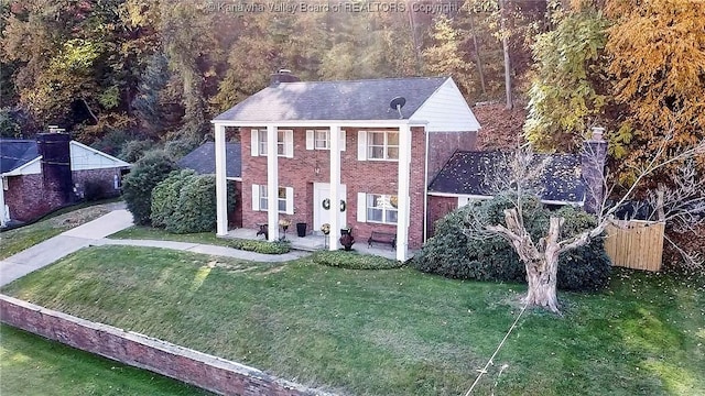 view of front of property featuring a front yard, brick siding, and a chimney