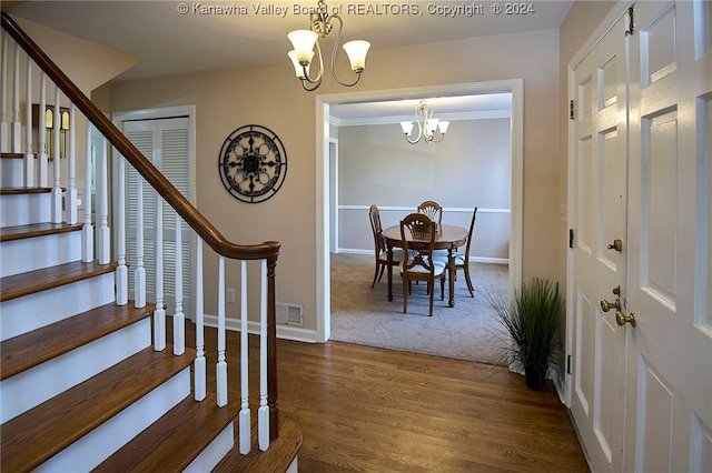 foyer entrance with dark hardwood / wood-style flooring, an inviting chandelier, and ornamental molding