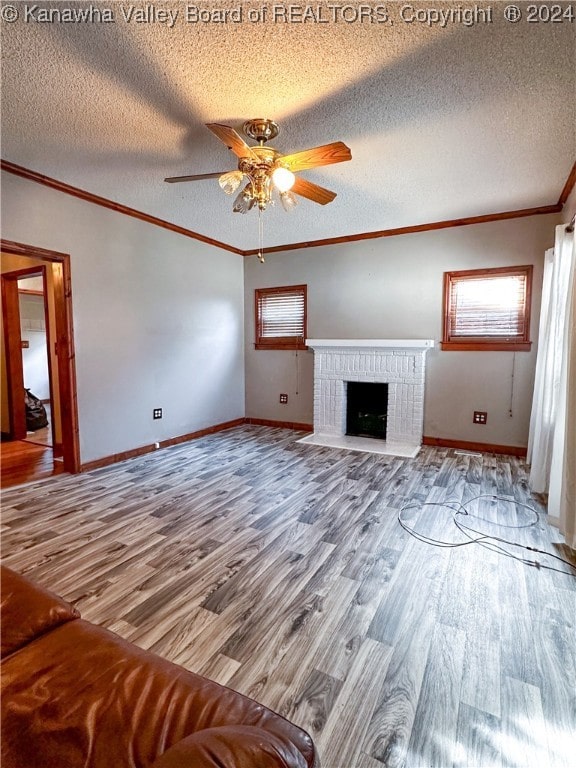 unfurnished living room with hardwood / wood-style floors, a fireplace, ceiling fan, and a textured ceiling