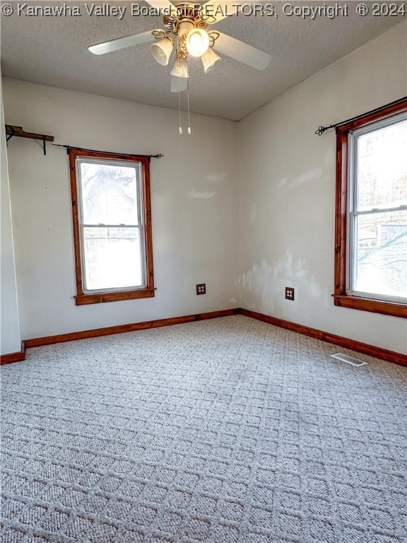 unfurnished room featuring a textured ceiling, plenty of natural light, and ceiling fan