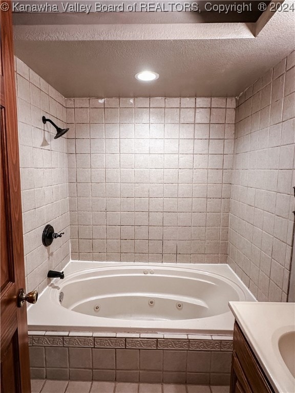 bathroom with vanity, a textured ceiling, and tiled shower / bath