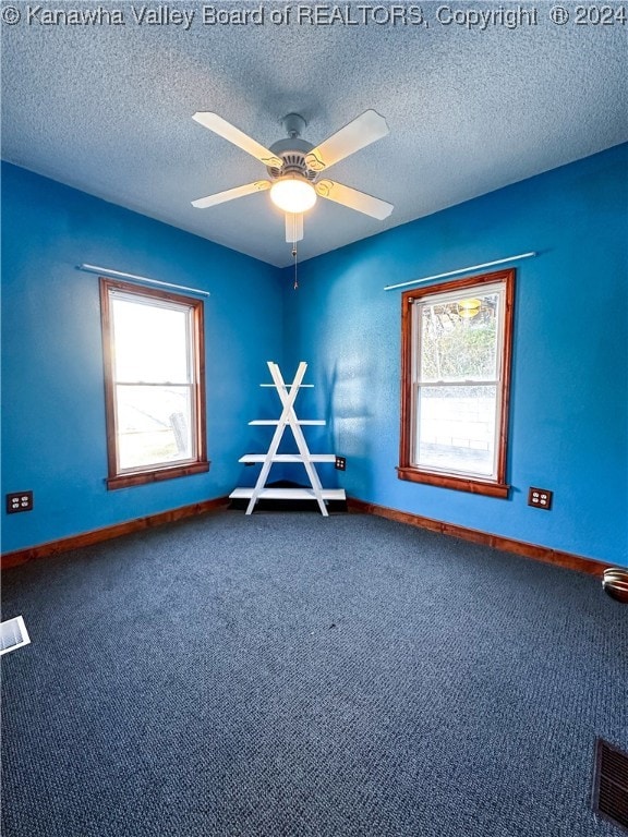 carpeted spare room featuring ceiling fan and a textured ceiling