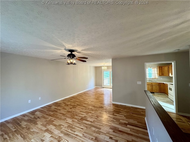 spare room featuring ceiling fan, light hardwood / wood-style floors, sink, and a textured ceiling