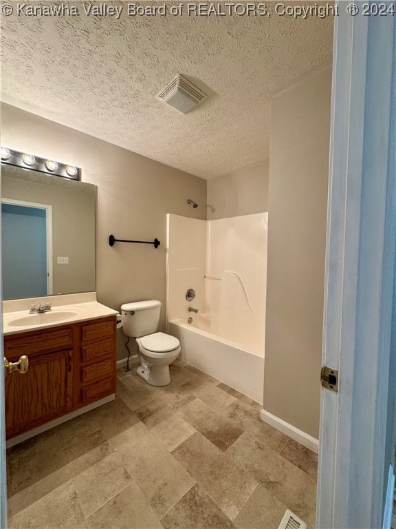 full bathroom featuring washtub / shower combination, vanity, a textured ceiling, and toilet