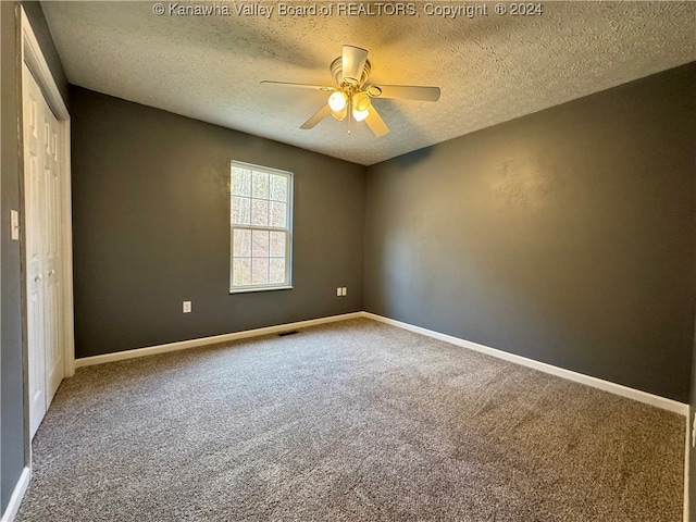 carpeted empty room featuring ceiling fan and a textured ceiling